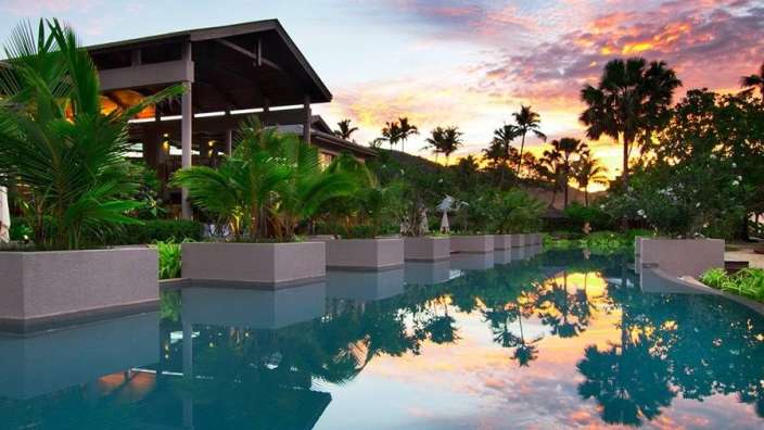 Ein großer Swimmingpool mit Palmen und einem Gebäude im Hintergrund