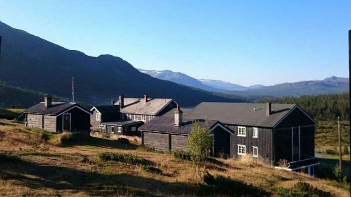 Eine Gruppe von Häusern auf einem Hügel mit Bergen im Hintergrund