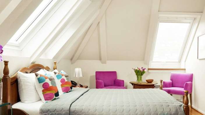 Ein Schlafzimmer mit einem Bett und zwei lila Stühlen