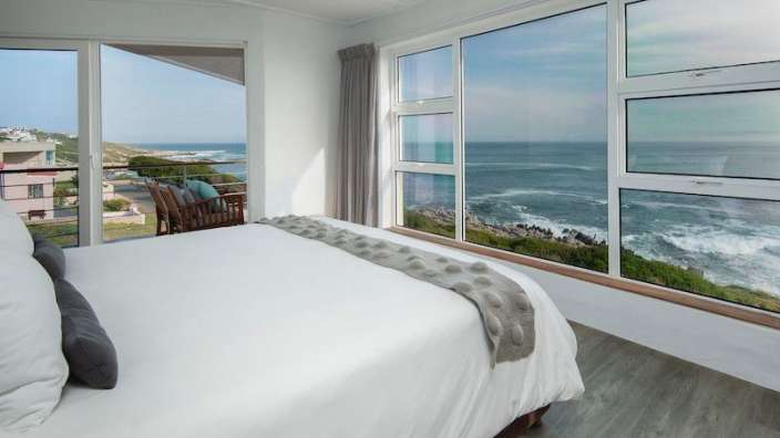 Ein Schlafzimmer mit einem Bett und einem großen Fenster mit Blick auf das Meer