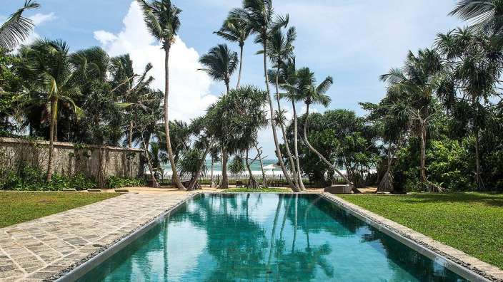 Ein großer Swimmingpool umgeben von Palmen und Gras