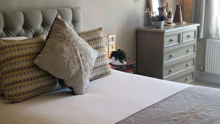 Ein Bett mit vielen Kissen und einer Kommode