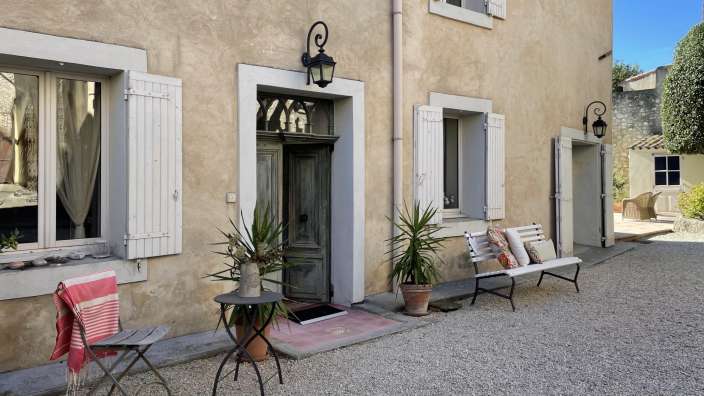 Ein Haus mit weißen Fensterläden und einer Bank davor
