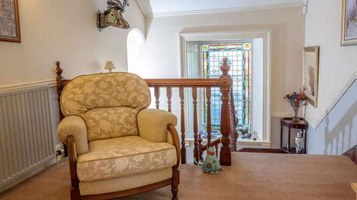 Ein Stuhl sitzt auf einer Treppe neben einem Buntglasfenster