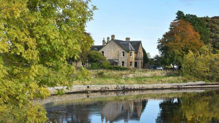 Ein großes Haus steht neben einem Fluss
