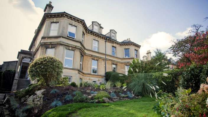 Ein großes Gebäude mit vielen Fenstern und einem Garten davor