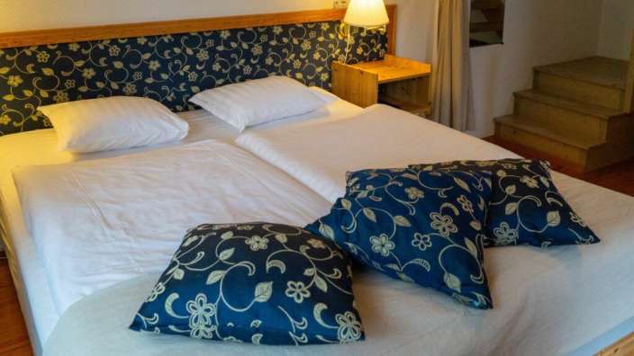 Ein Bett mit blauen Kissen und weißen Bettwäschen