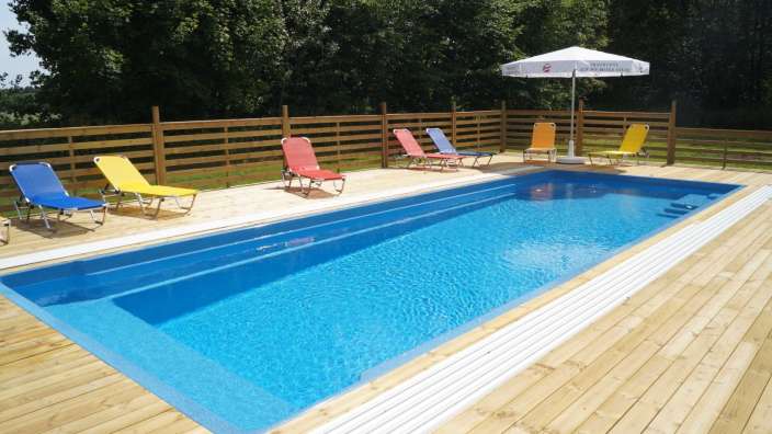 Ein blauer Pool mit Liegestühlen und einem weißen Regenschirm