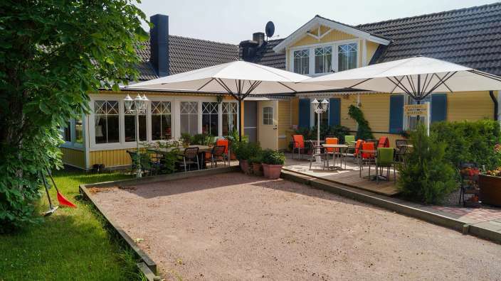 Eine Terrasse mit Tisch und Stühlen vor einem gelben Haus
