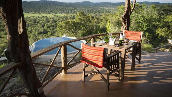 Ein Tisch und Stühle auf einer Terrasse mit Blick auf einen Pool