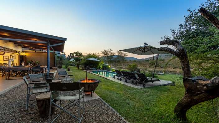Eine Terrasse mit Stühlen und einem Feuerplatz neben einem Swimmingpool