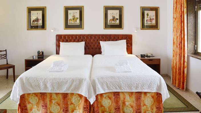 Ein Schlafzimmer mit zwei Betten und vier Gemälden an der Wand