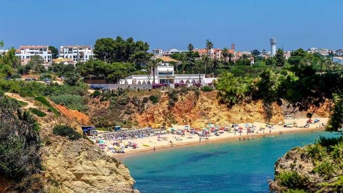 Ein Strand mit vielen Sonnenschirmen und einer Stadt im Hintergrund