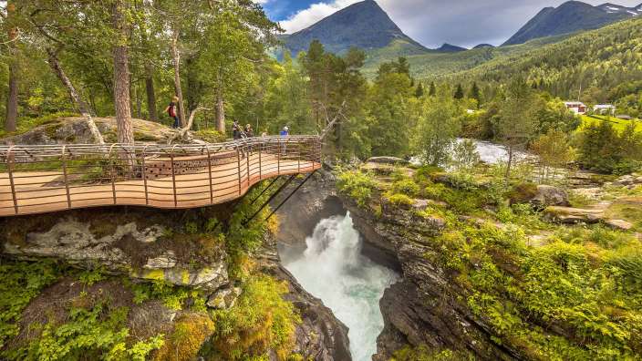 Menschen stehen auf einer Brücke über einen Wasserfall
