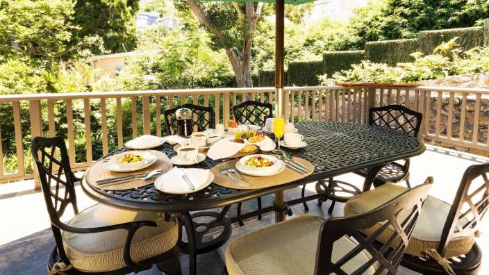 Eine Terrasse mit einem Tisch und Stühlen und einem grünen Regenschirm