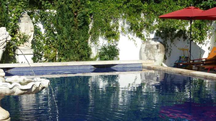 Ein Pool mit einem Brunnen und einem roten Regenschirm