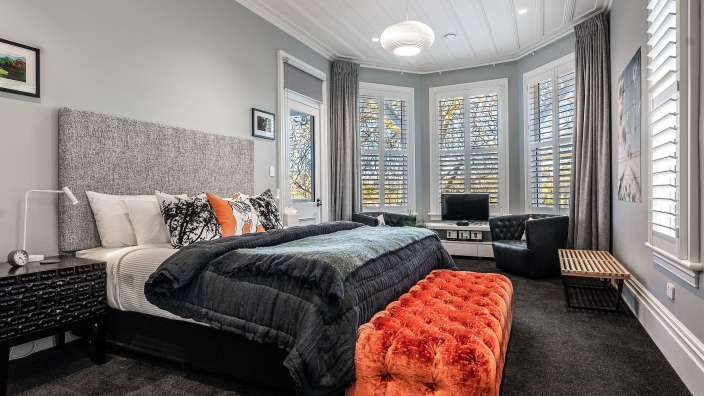 Ein Schlafzimmer mit einem großen Bett und einem orangefarbenen Hocker