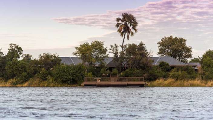 Ein Haus steht am Ufer eines Sees mit einer Palme davor