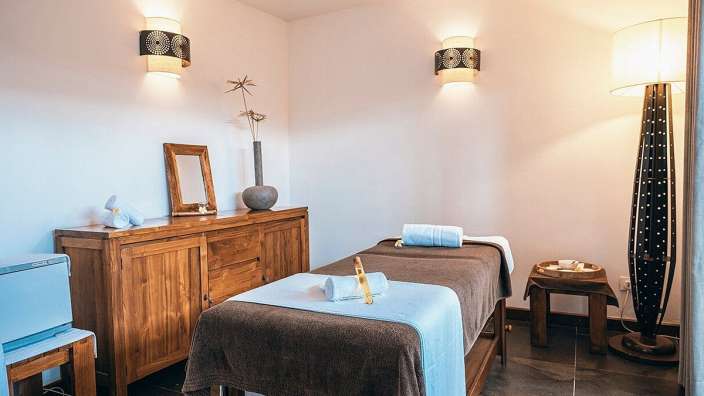 Ein Behandlungsraum mit Massageliegen und warmem Licht.