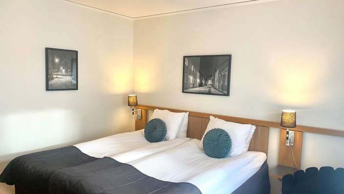 Ein Hotelzimmer mit zwei Betten und zwei Bildern an der Wand