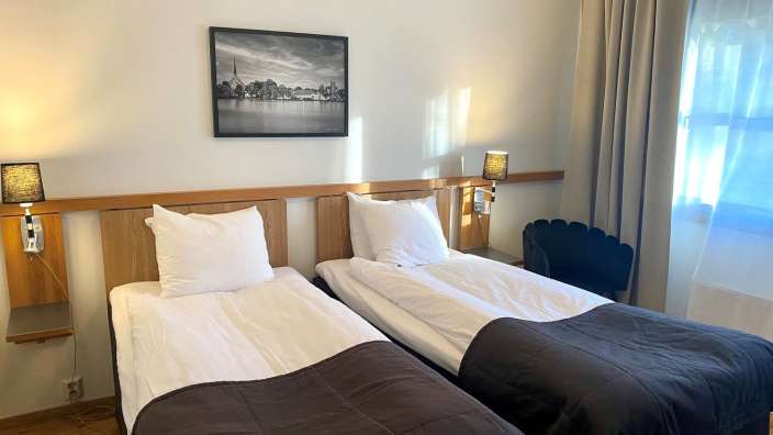 Ein Hotelzimmer mit zwei Betten und einem Gemälde an der Wand