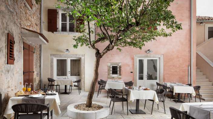 Eine Terrasse mit Tischen und Stühlen und einem Baum in der Mitte