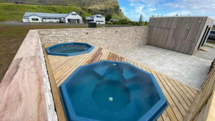 Zwei Whirlpools auf einem Holzdeck mit einem Berg im Hintergrund