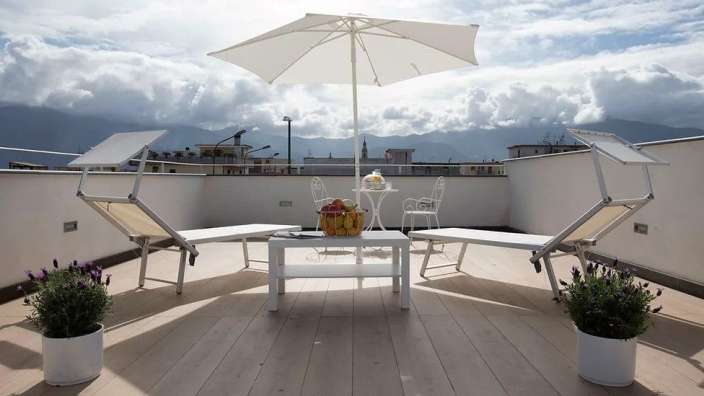 Eine Terrasse mit einem Tisch und Stühlen und einem weißen Regenschirm