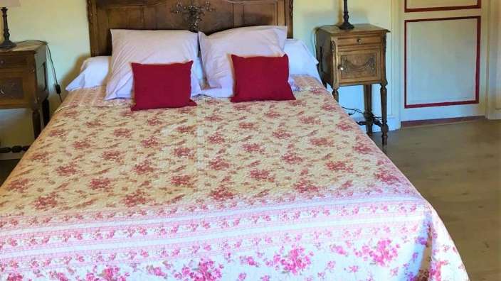 Ein Bett mit einer Blumendecke und roten Kissen darauf