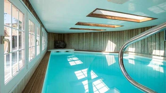 Ein sehr langes Schwimmbad in einem Haus mit vielen Fenstern