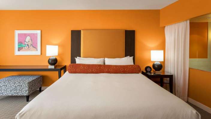 Ein Hotelzimmer mit orangefarbenen Wänden und einem Bett
