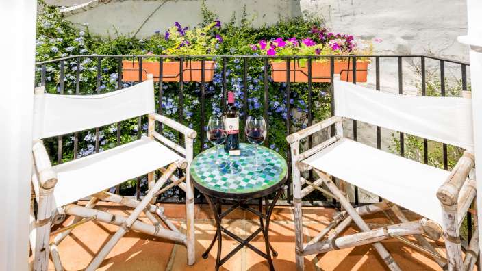 Ein Tisch mit zwei Gläsern und einer Flasche Wein auf einem Balkon