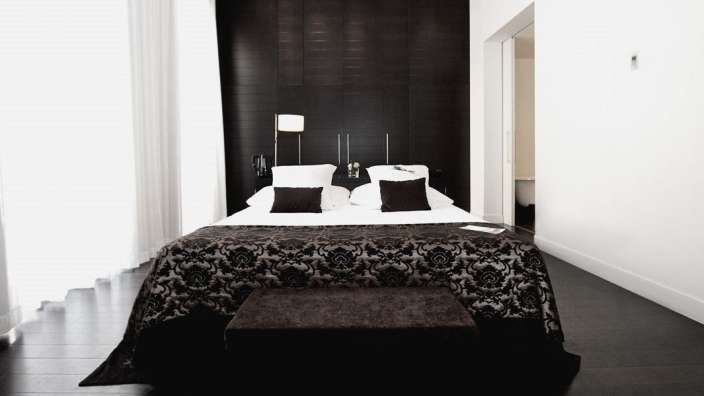 Ein schwarz-weißes Schlafzimmer mit einem Bett und einer Bank