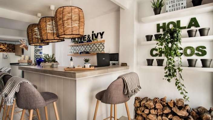 Eine Küche mit einer Bar und Stühlen und einem Schild an der Wand, das sagt hola chicos