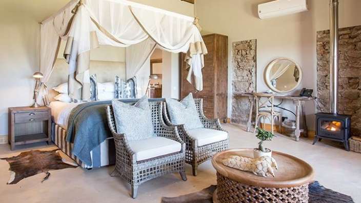 Ein Schlafzimmer mit Himmelbett, Stühlen und einem Tisch