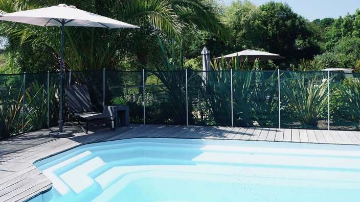 Ein weißer Regenschirm steht neben einem Swimmingpool