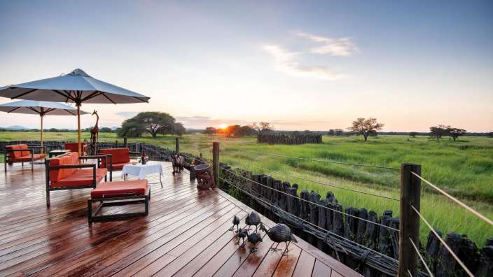 Ein Deck mit Möbeln und Sonnenschirmen mit Blick auf eine Wiese
