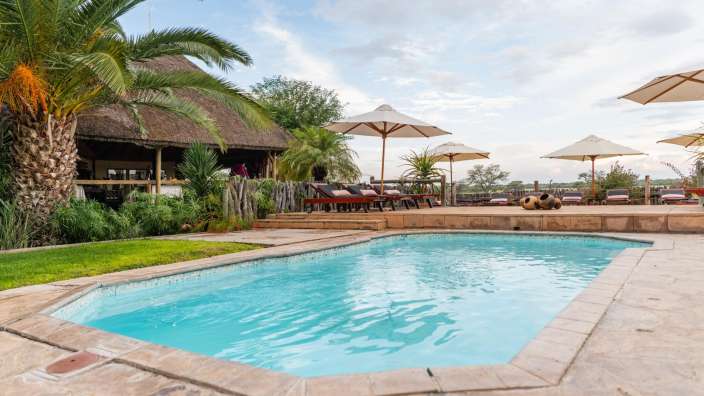 Ein großer Pool mit Liegestühlen und Sonnenschirmen umgeben