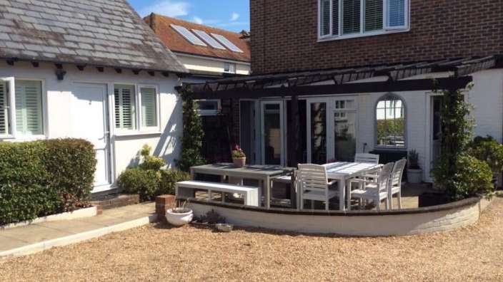 Eine Terrasse mit einem Tisch und Stühlen vor einem Backsteinhaus