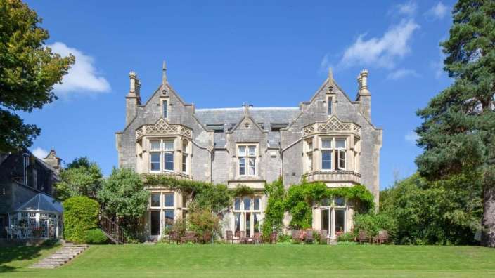 Ein großes Haus mit vielen Fenstern sitzt auf einer grünen Wiese