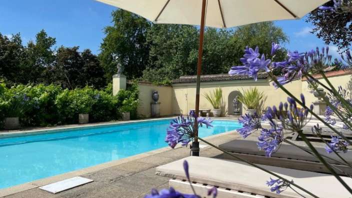 Ein weißer Regenschirm steht in der Nähe eines Swimmingpools