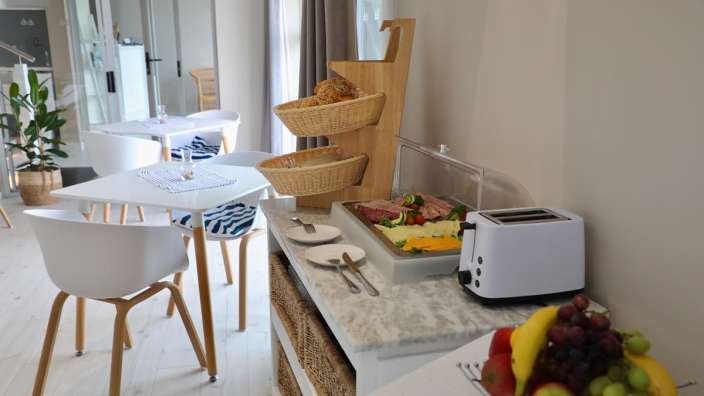 Ein Tisch und Stühle stehen neben einem Toaster und einem Obstkorb