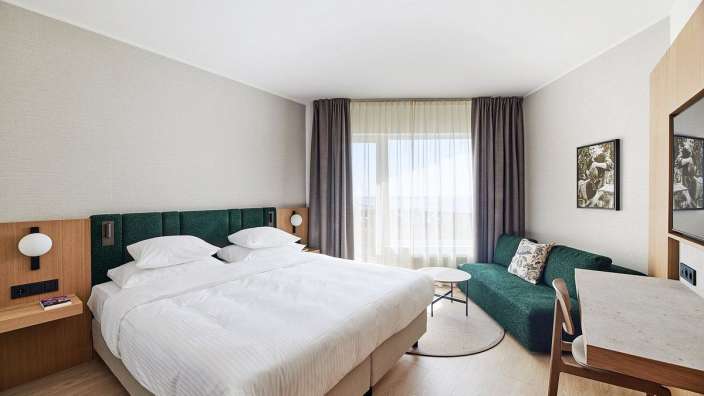 Ein Hotelzimmer mit einem Bett und einer grünen Couch