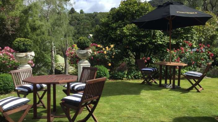 Ein garten mit einem tisch und stühlen und einem schwarzen regenschirm