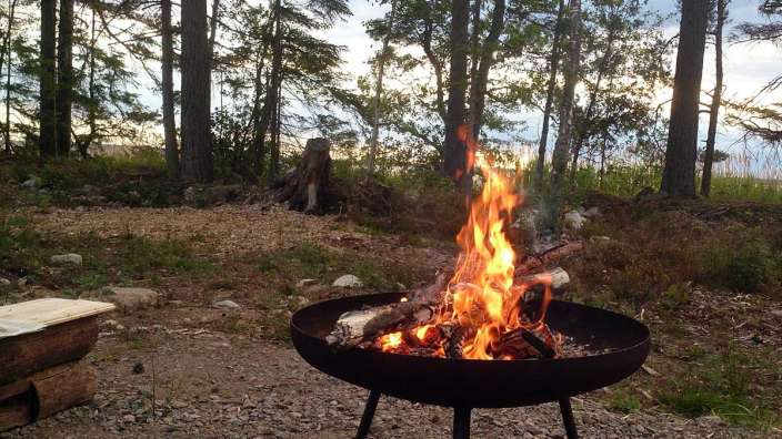 Ein Feuer brennt in einer Feuerschale im Wald