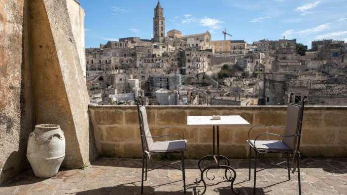 Ein Tisch und Stühle auf einem Balkon mit Blick auf eine Stadt