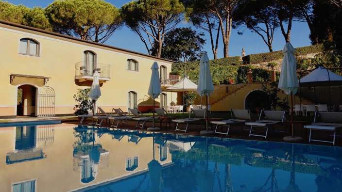 Liegestühle und Sonnenschirme umgeben einen großen Swimmingpool