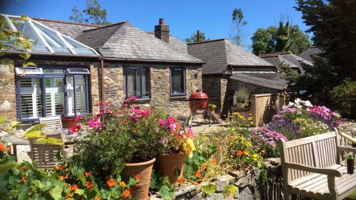 Eine Bank sitzt in einem Garten vor einem Steinhaus