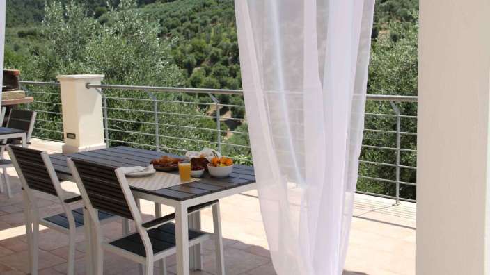 Ein Tisch und Stühle auf einem Balkon mit Blick auf die Berge