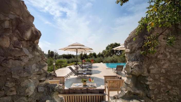 Eine Terrasse mit Liegestühlen und Sonnenschirmen neben einem Pool